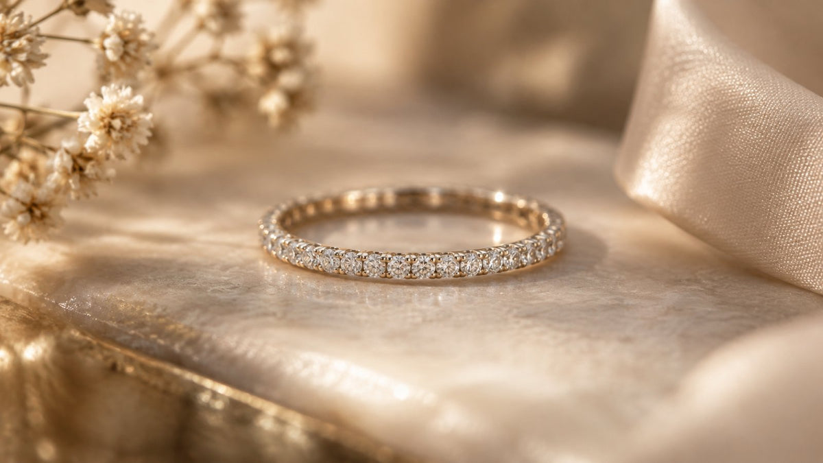 A slim diamond eternity promise ring on a soft, romantic neutral surface