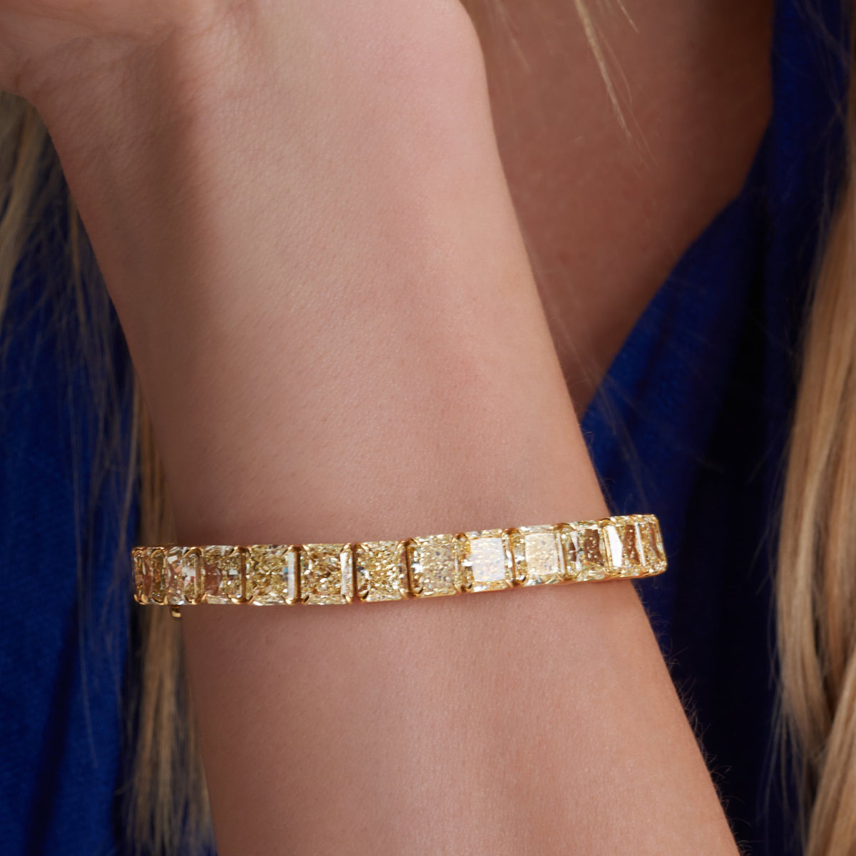 33.52 CT Radiant Cut Fancy Yellow Diamond Tennis Bracelet in 18K Yellow Gold, worn on model, view 1 - fine jewelry in San Francisco